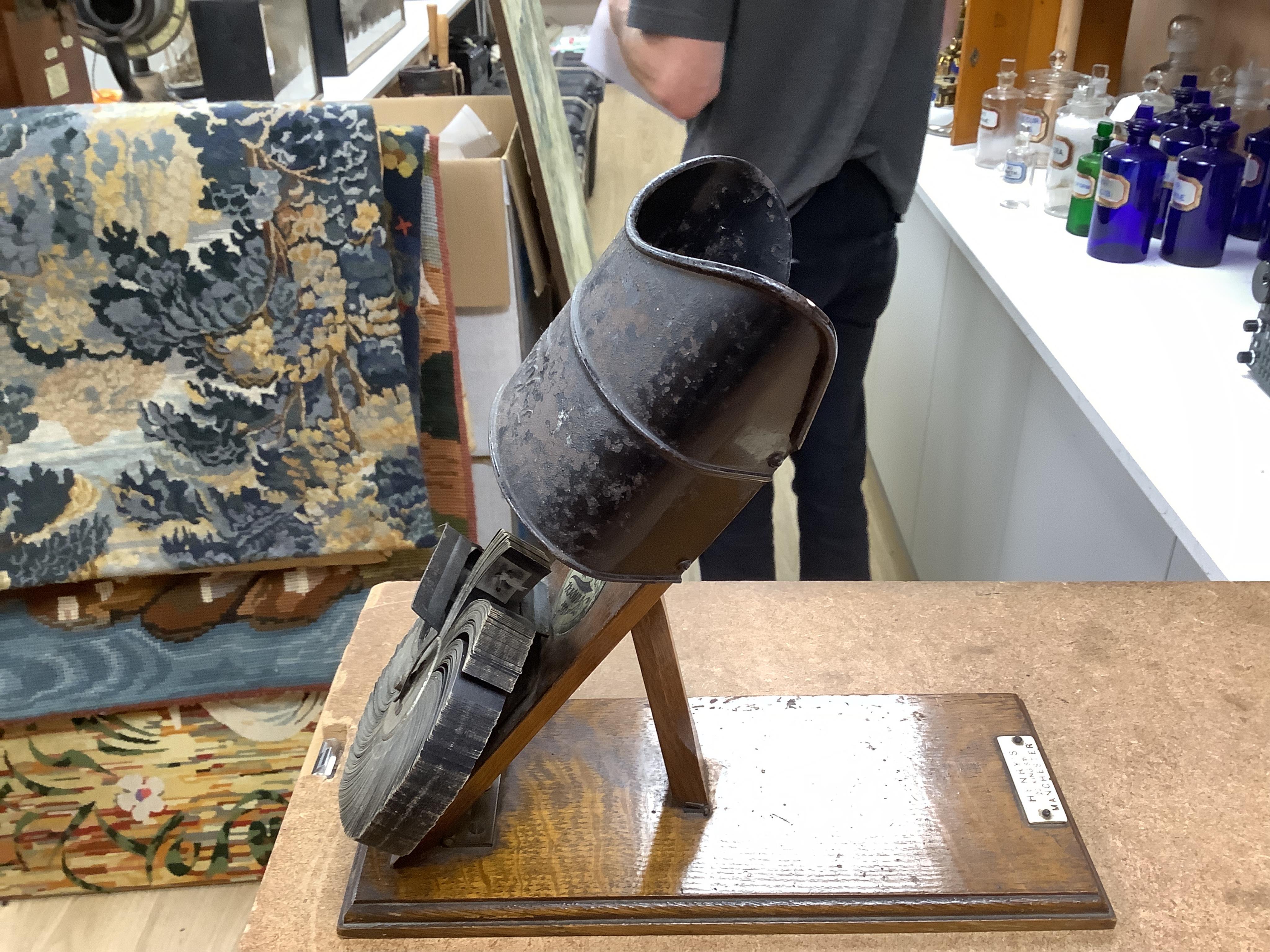 An early 20th century Kinora cinematographic viewer by Bond’s Ltd., 138 New Bond Street, c.1910, with six reels of flip card picture films, black painted steel and oak construction, with an ivory retail label for Henry’s